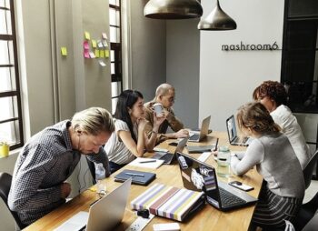 A group of people sitting at a table with laptops.