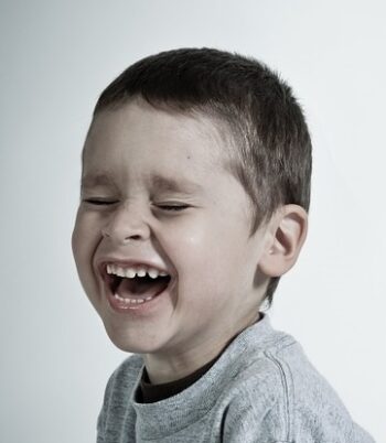 A young boy is laughing with his mouth open.